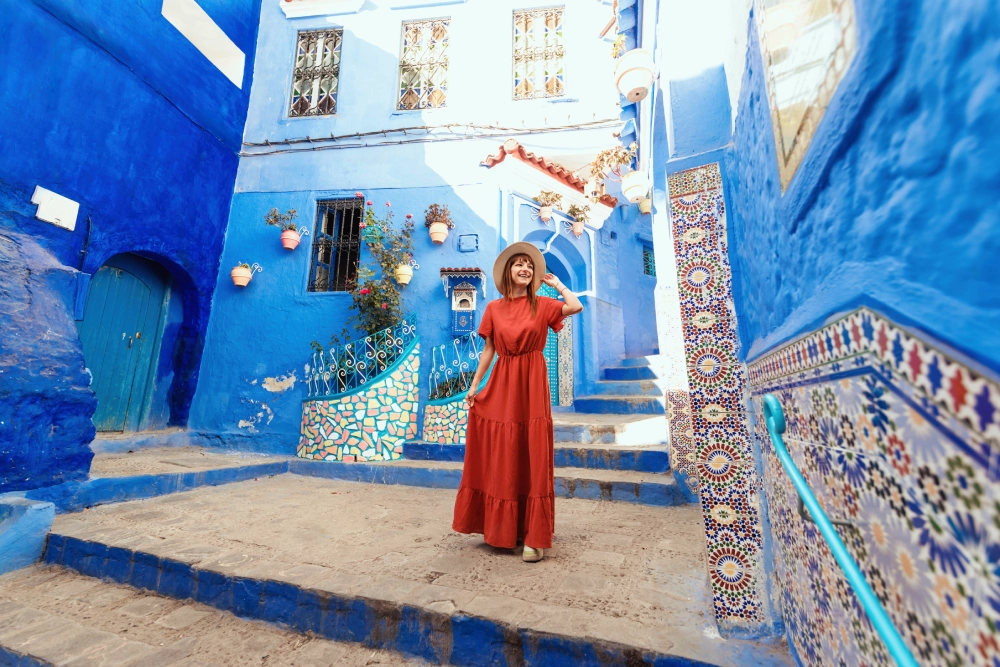 A woman in red dress standing on steps near blue buildings.