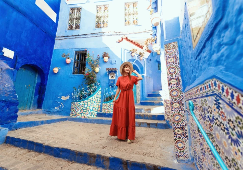 A woman in red dress standing on steps near blue buildings.